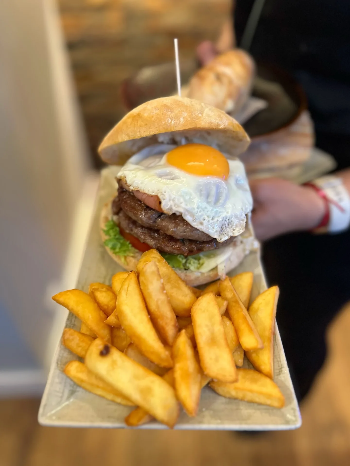 Burger topped with a fried egg, served with fries